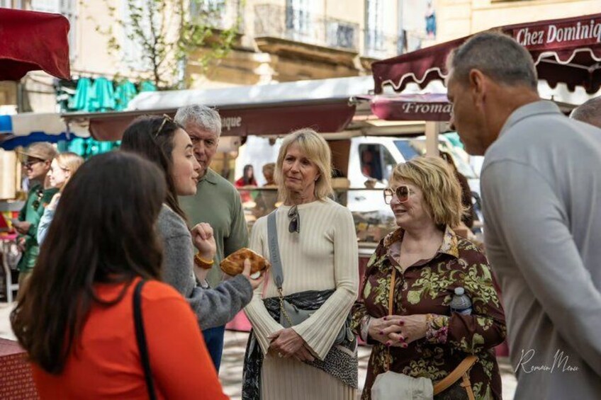 A group of people at an outdoor market with food stalls. 1