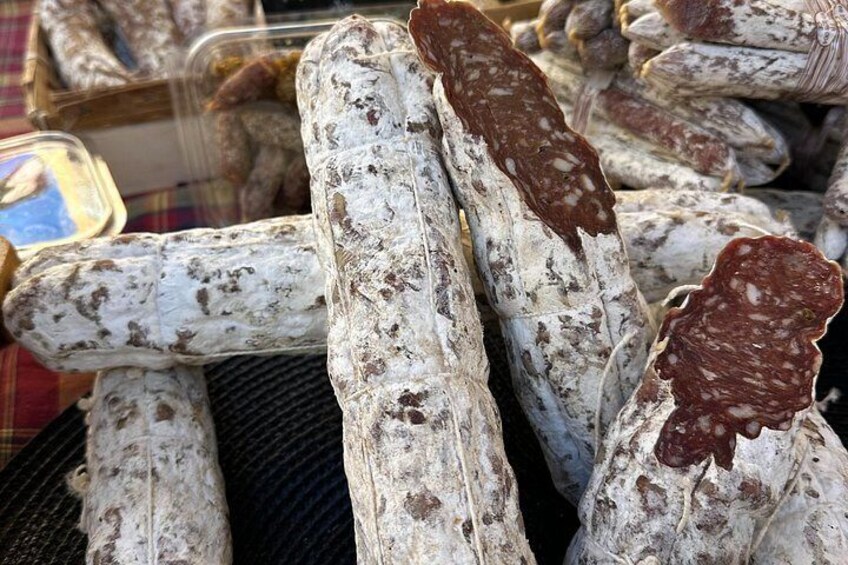 A display of various types of cured meats, including salami and other sausages, arranged on a table. 2