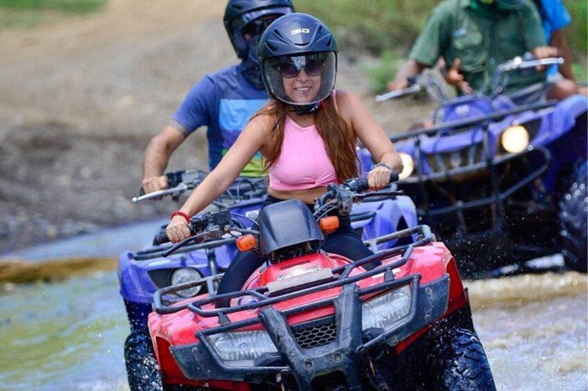 Iemand rijdt op een quad door een ondiepe waterovergang. 1