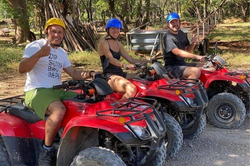 Three people on red ATVs in a wooded area. 2