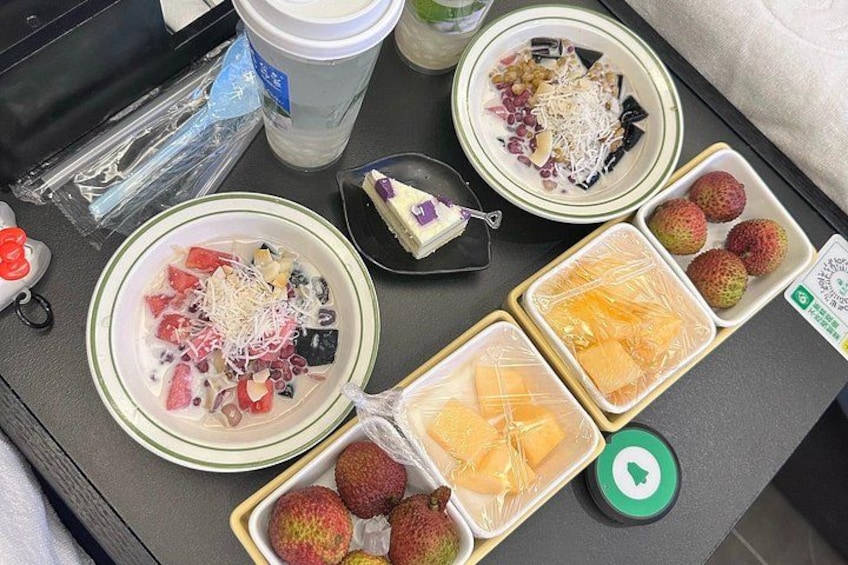 A table with various food items including bowls of fruit, a cup, and containers of packaged snacks. 5