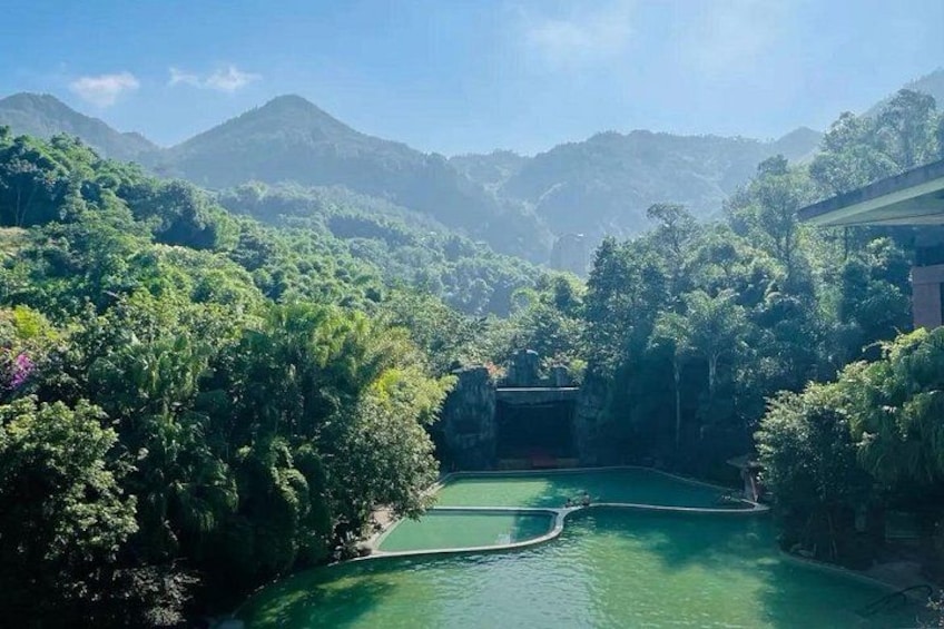 A lush green valley with a river, surrounded by dense forest and mountains. 1