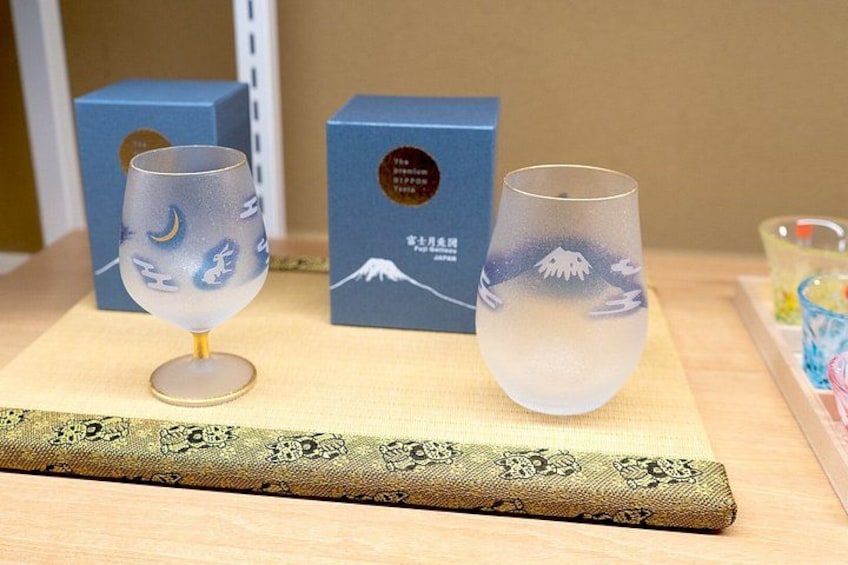 Two decorative glasses with a snowy mountain design, placed on a table with a patterned cloth and a blue box in the background. 5
