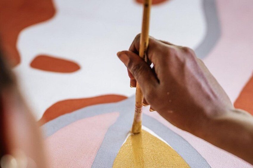 A hand holding a paintbrush applying yellow paint to a canvas. 2