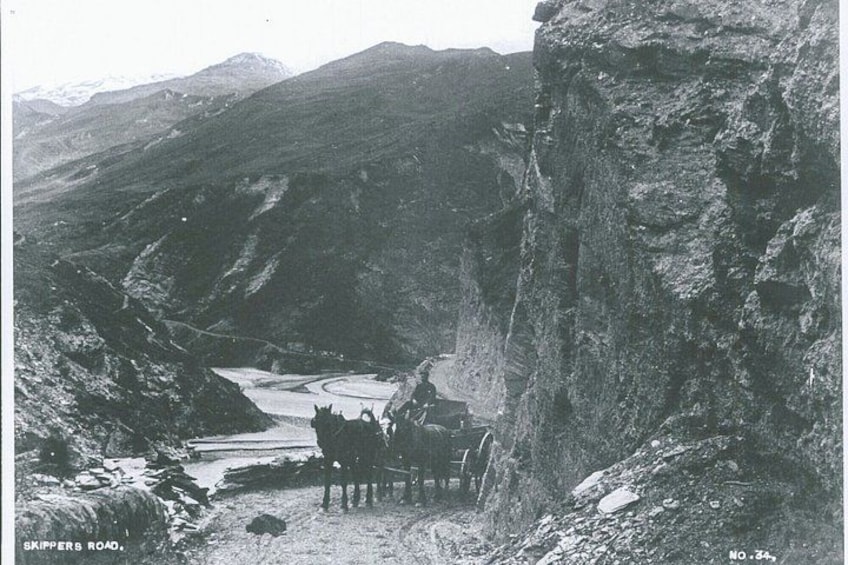 Un cañón estrecho con un río, un carruaje tirado por caballos y un risco rocoso. 4