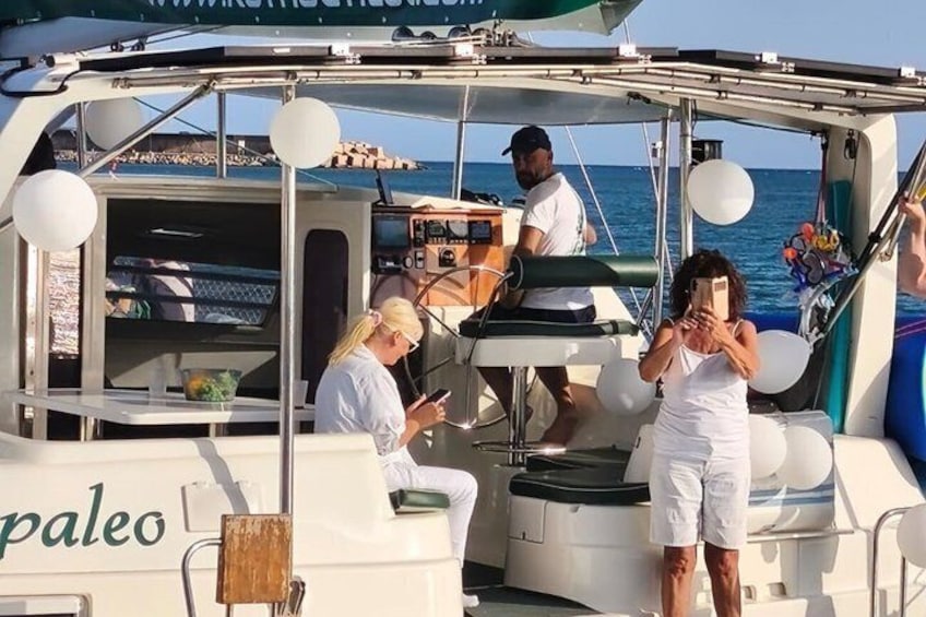 A boat with 'paleo' written on the side, a person standing on the deck, and another person at the helm. 3