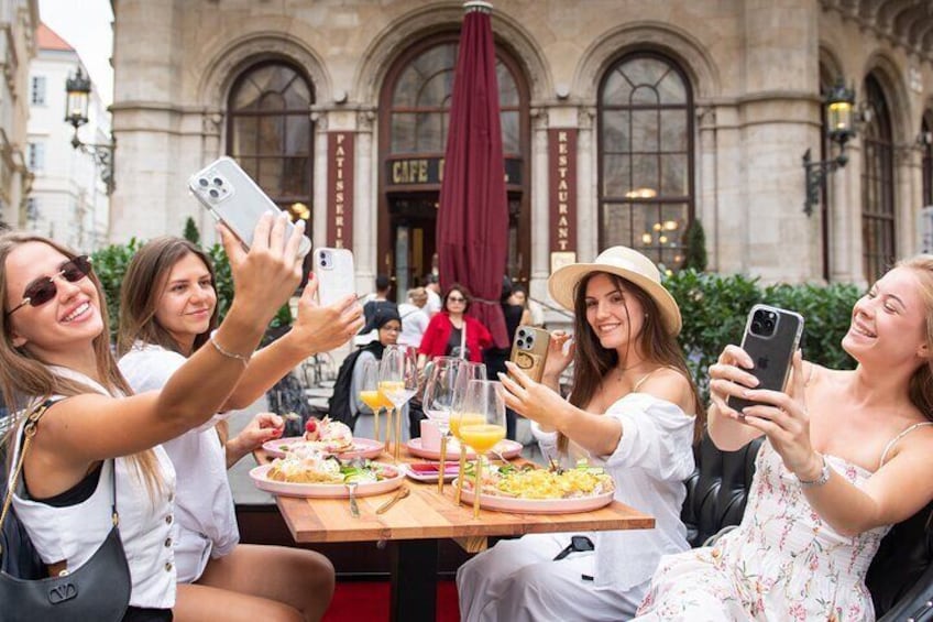 A group of people taking a selfie at a cafe with a table full of food and drinks. 3
