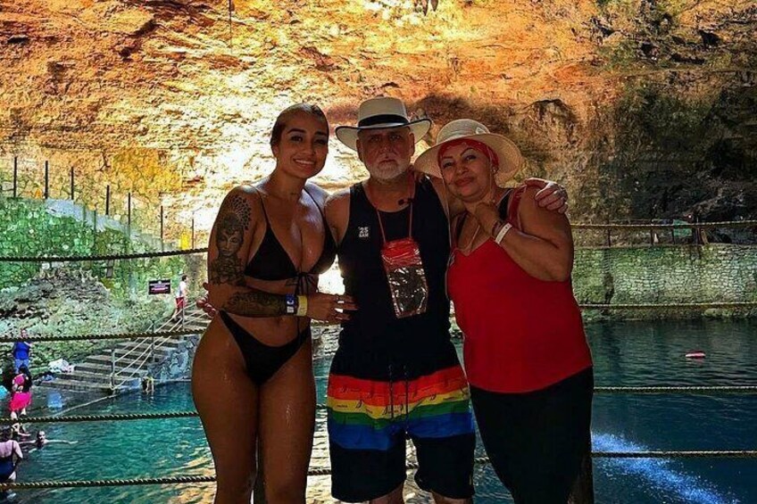Three people standing by a pool with a rocky cave background. 2