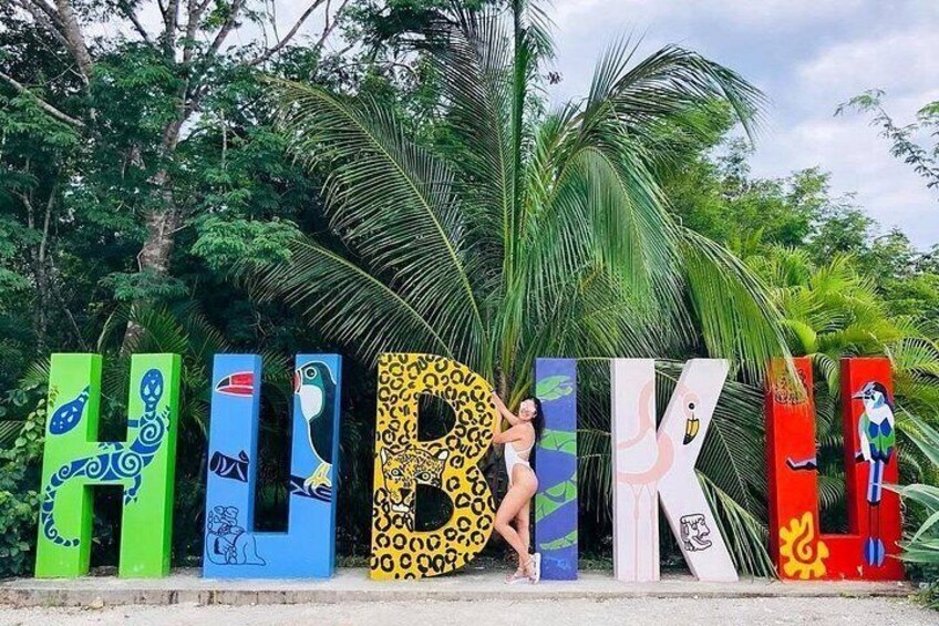 Colorful letters spelling 'HUBIKI' with various animal and bird designs, set against a backdrop of palm trees and greenery. 4