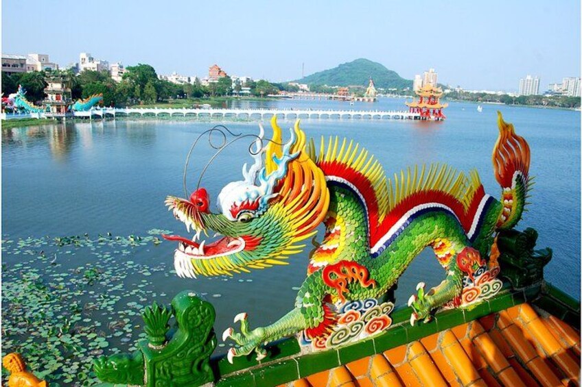 Un'imbarcazione a forma di drago colorata su un fiume, con un ponte e degli edifici sullo sfondo. 3