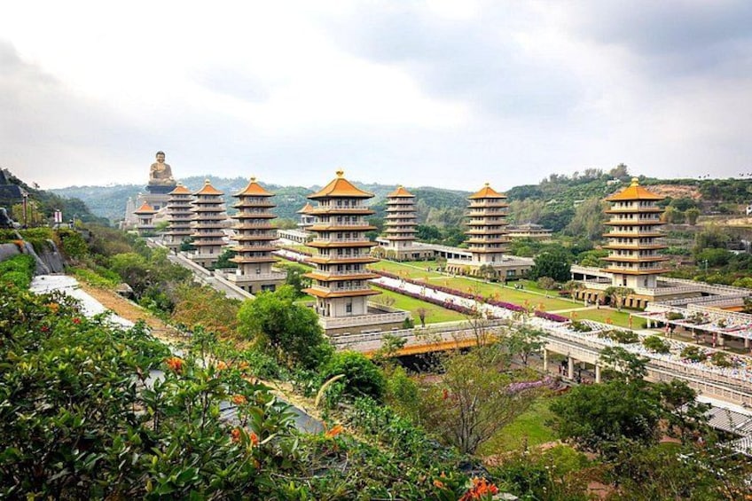 A pagoda-style building complex with a large Buddha statue in the background. 5