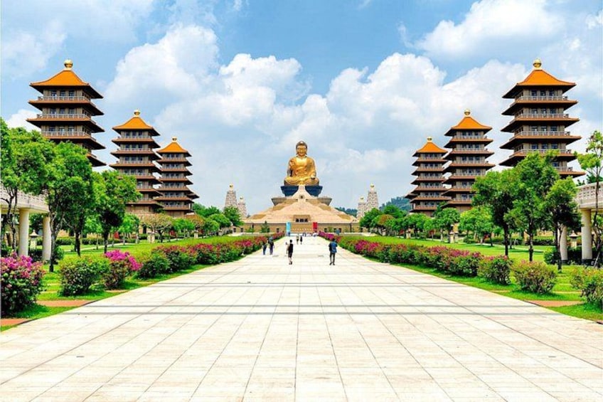 A large Buddha statue flanked by pagoda-style buildings, with a paved walkway leading to it. 2