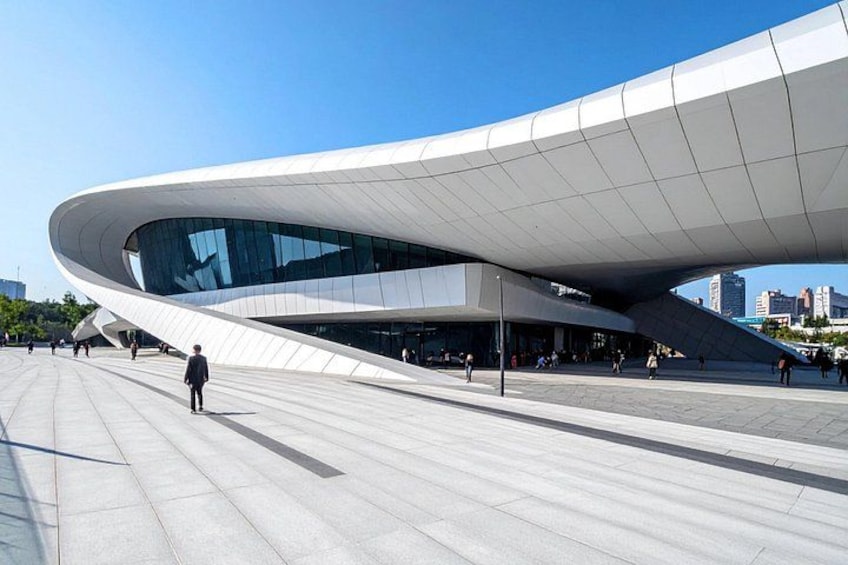 A modern architectural building with a curved design and a spacious plaza. 4