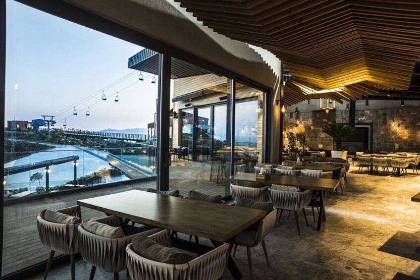 A modern dining area with large windows overlooking a river and a bridge. 3