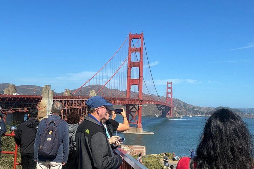 The Golden Gate Bridge, a red suspension bridge, with people taking photos. 3