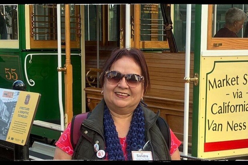 A person standing in front of a green and yellow bus with a sign that reads 'Market St - via California Van Ness.' 5