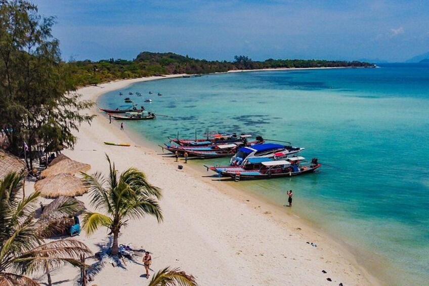 A beach with clear turquoise water, palm trees, and several boats anchored near the shore. 2