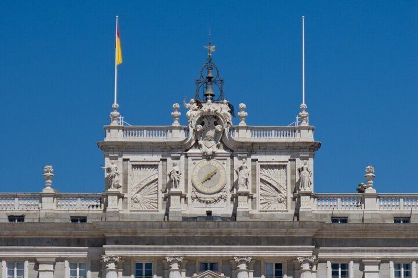 Un edificio imponente con arquitectura ornamentada, un reloj destacado y una bandera. 5