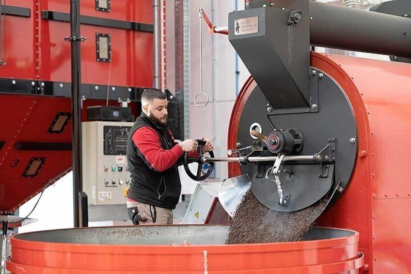 Een persoon bedient een grote industriële machine met een trechter en bedieningspaneel. 3