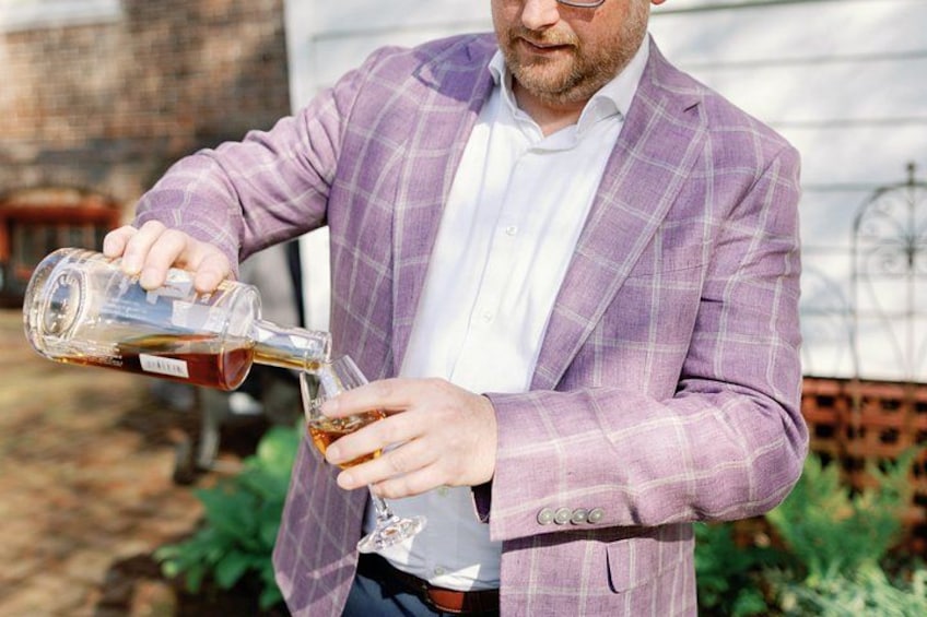 En person hælder væske fra en flaske i et glas. 3