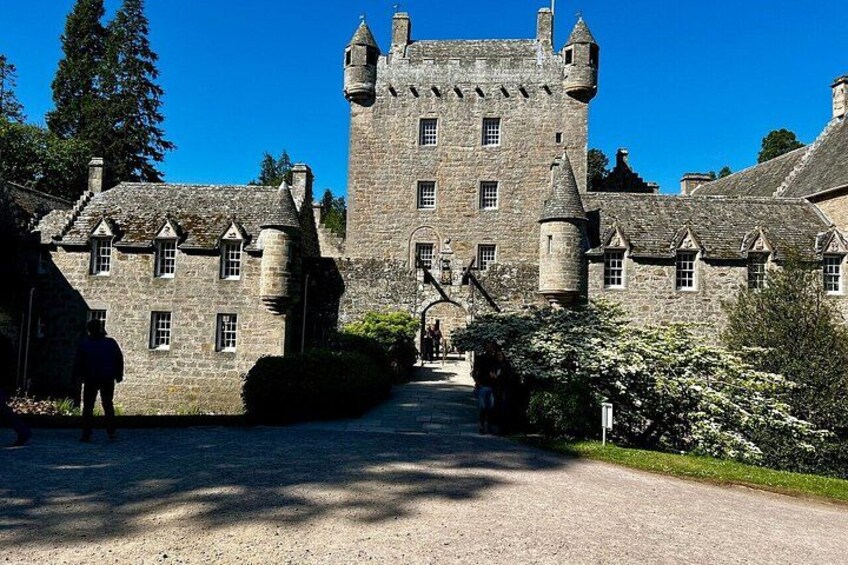A castle with a large tower, a gravel driveway, and a person walking. 2