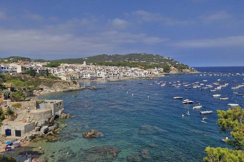 A coastal town with clear blue waters, boats, and white buildings. 2