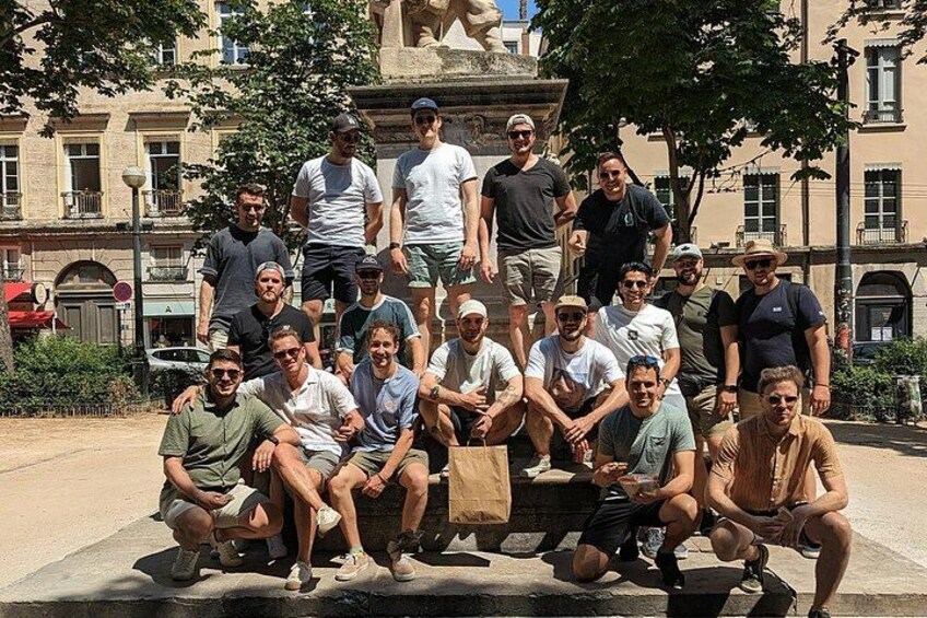 En gruppe mennesker poserer på et offentligt torv med en statue i baggrunden. 2