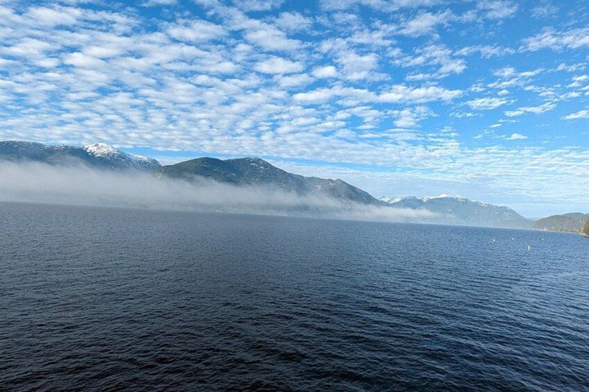 A calm lake with mountains in the background and a partly cloudy sky. 2
