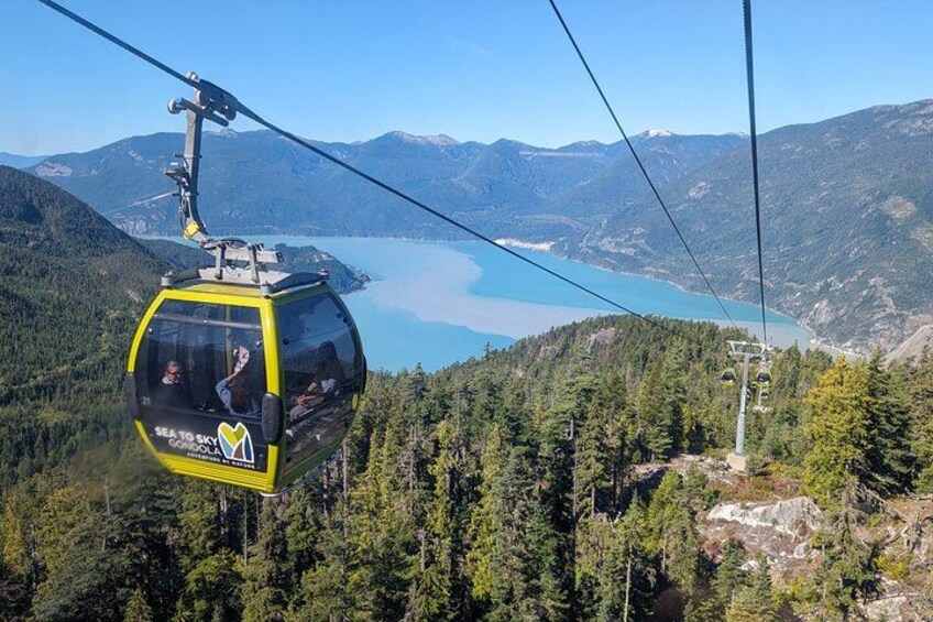 A cable car with a lake and mountains in the background. 1