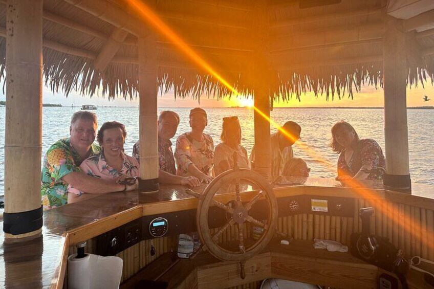 Un grupo de personas en un bote con techo de paja disfrutando del atardecer. 5