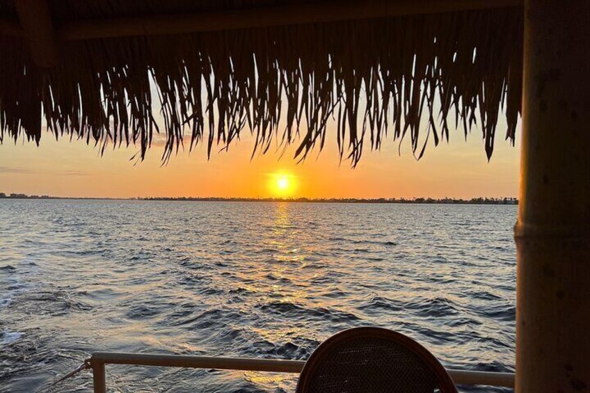 Un atardecer sobre una masa de agua con una estructura de techo de paja. 4