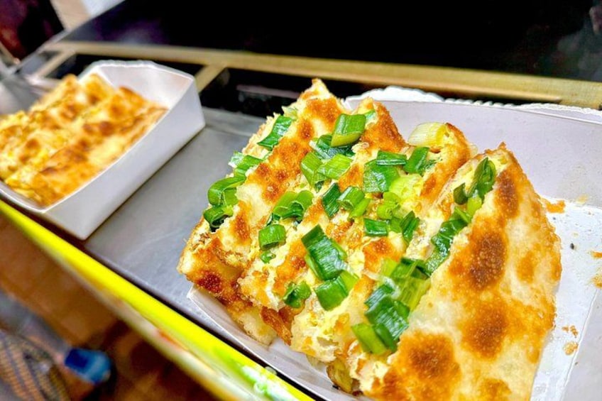 Una porción de pizza con cebollas verdes en una bandeja. 3