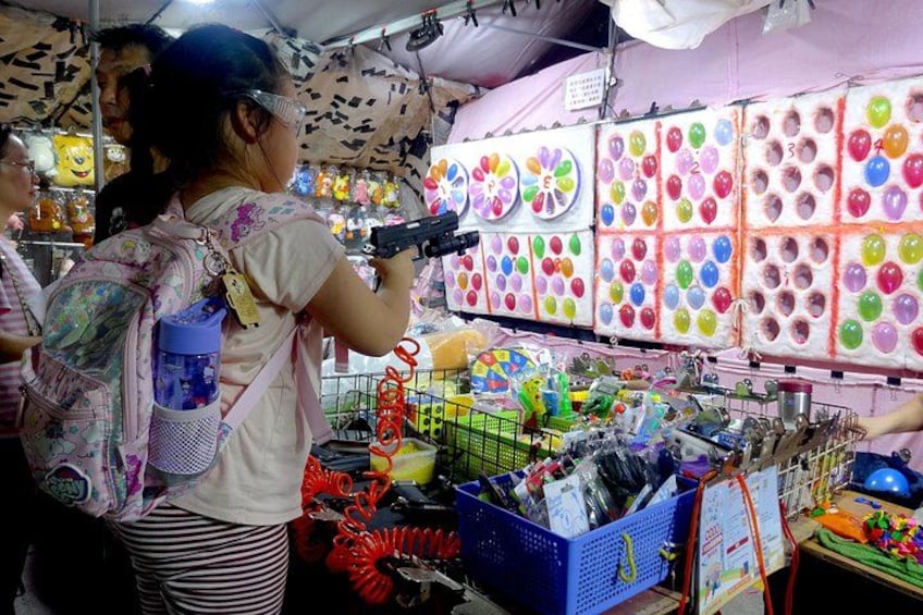 Un puesto de mercado con globos de colores, una cesta azul y varios artículos a la vista. 2