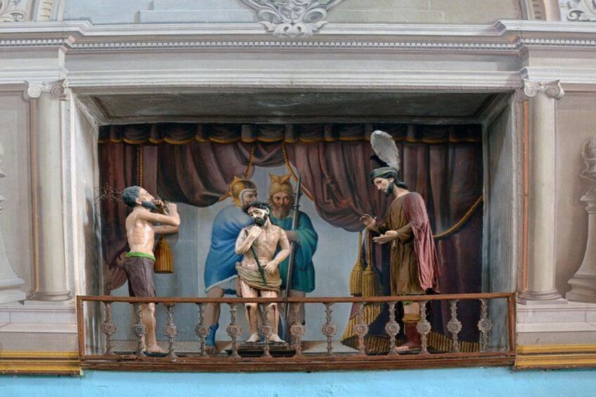 A classical sculpture of four figures in a theatrical setting. 4