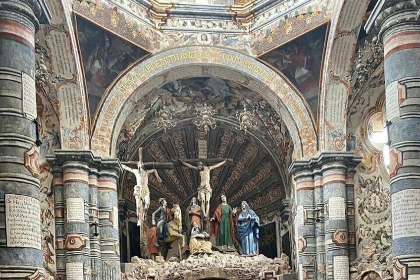 Een rijk versierd kerkinterieur met een groot kruisigevoorschouw, gedetailleerde houtsnijwerken en zuilen. 2