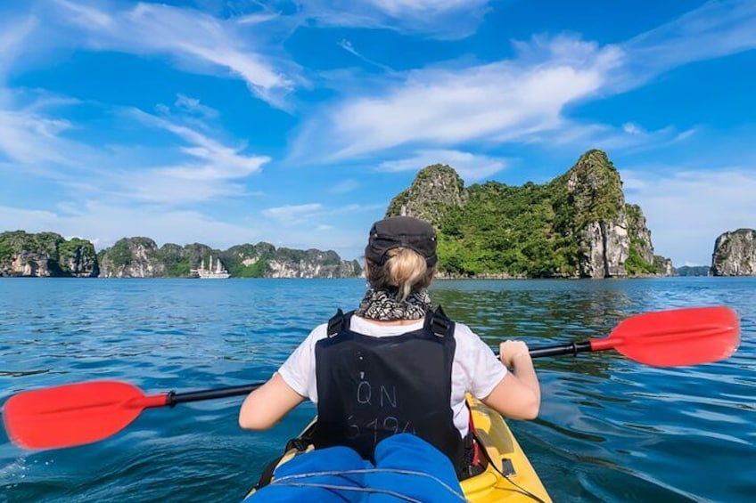A person kayaking on a calm sea with rocky cliffs in the background. 5