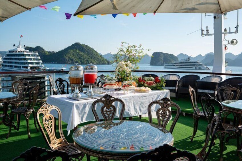 Een eetgedeelte met tafels en stoelen, een buffet en uitzicht op een cruiseschip en een bergachtig eiland. 4