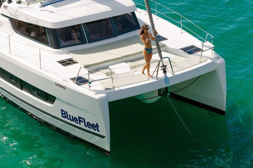 Een witte catamaran met de naam BlueFleet op turquoise water. 3