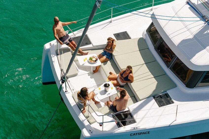 Een witte jacht genaamd CATSPACE met mensen aan dek, omringd door turquoise water. 5