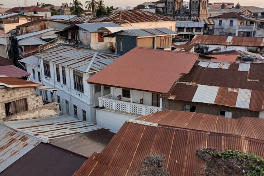 A densely packed urban area with a mix of residential buildings, some with red and rusted roofs, and a prominent white building with a balcony. 2