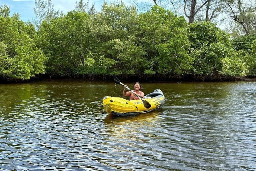 En person i en gul redningsflåde på en flod omgivet af frodig vegetation. 2
