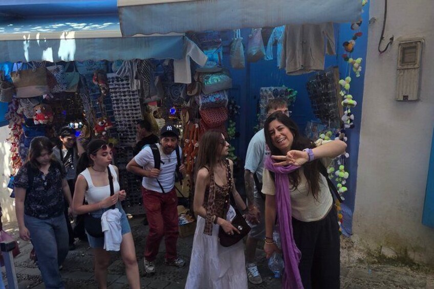 A group of people standing in front of a market stall with various items on display. 2