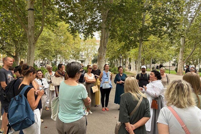 A group of people gathered in a park with trees and a paved walkway. 4