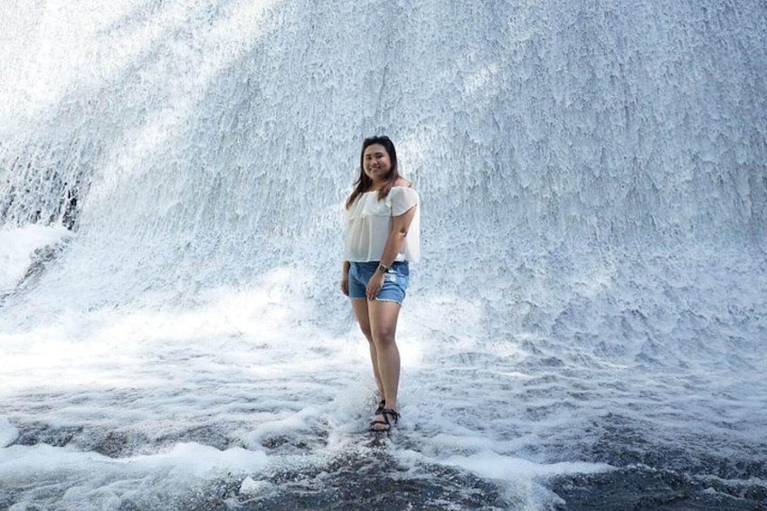 Een persoon staat voor een waterval. 3