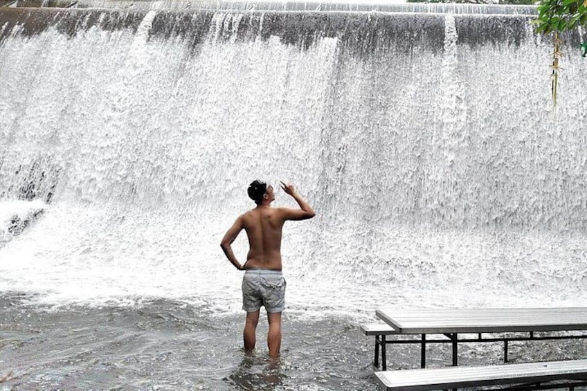 Een persoon staat in het water, met een waterval op de achtergrond. 2