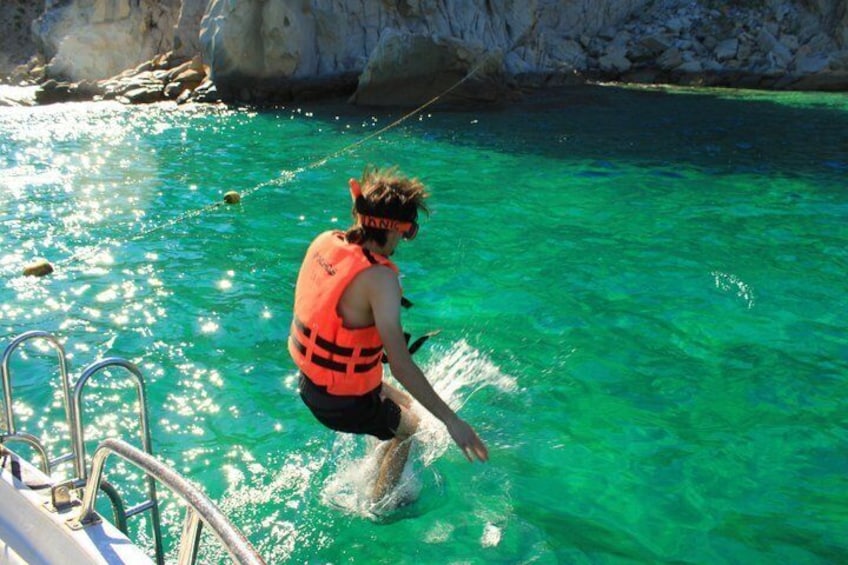 A person water skiing on a boat in clear turquoise water. 3