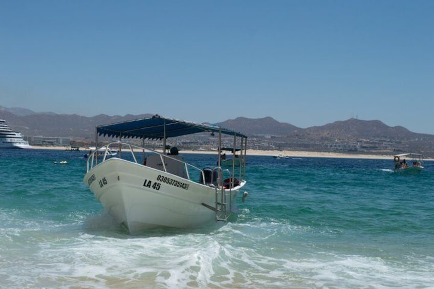 A boat named 'LA 45' with a canopy, a beach, and mountains in the background. 5