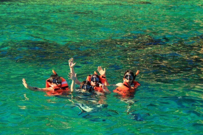 Three people snorkeling in clear turquoise water. 1