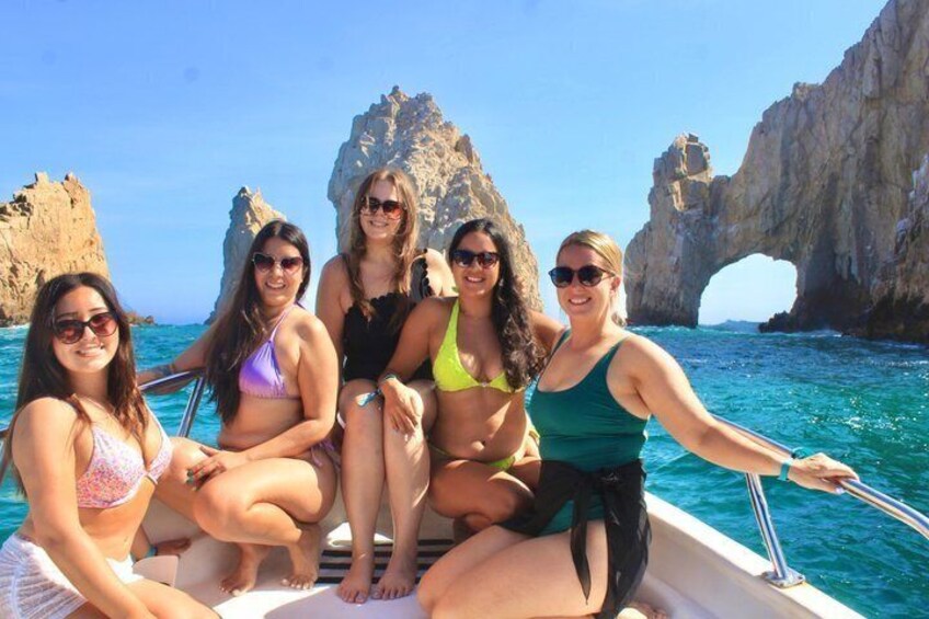 Un grupo de personas en un barco frente a un litoral rocoso y una formación arqueada natural. 2
