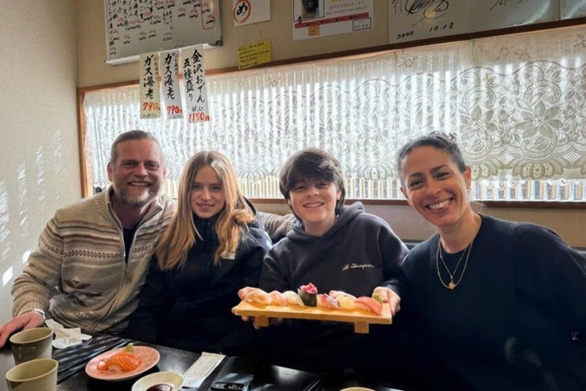 Four people sitting at a table with a plate of food, a cup, and a menu. 5